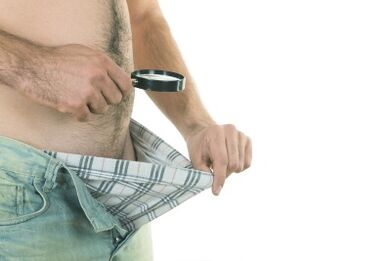Ein Mann betrachtet seinen Penis und möchte ihn vergrößern